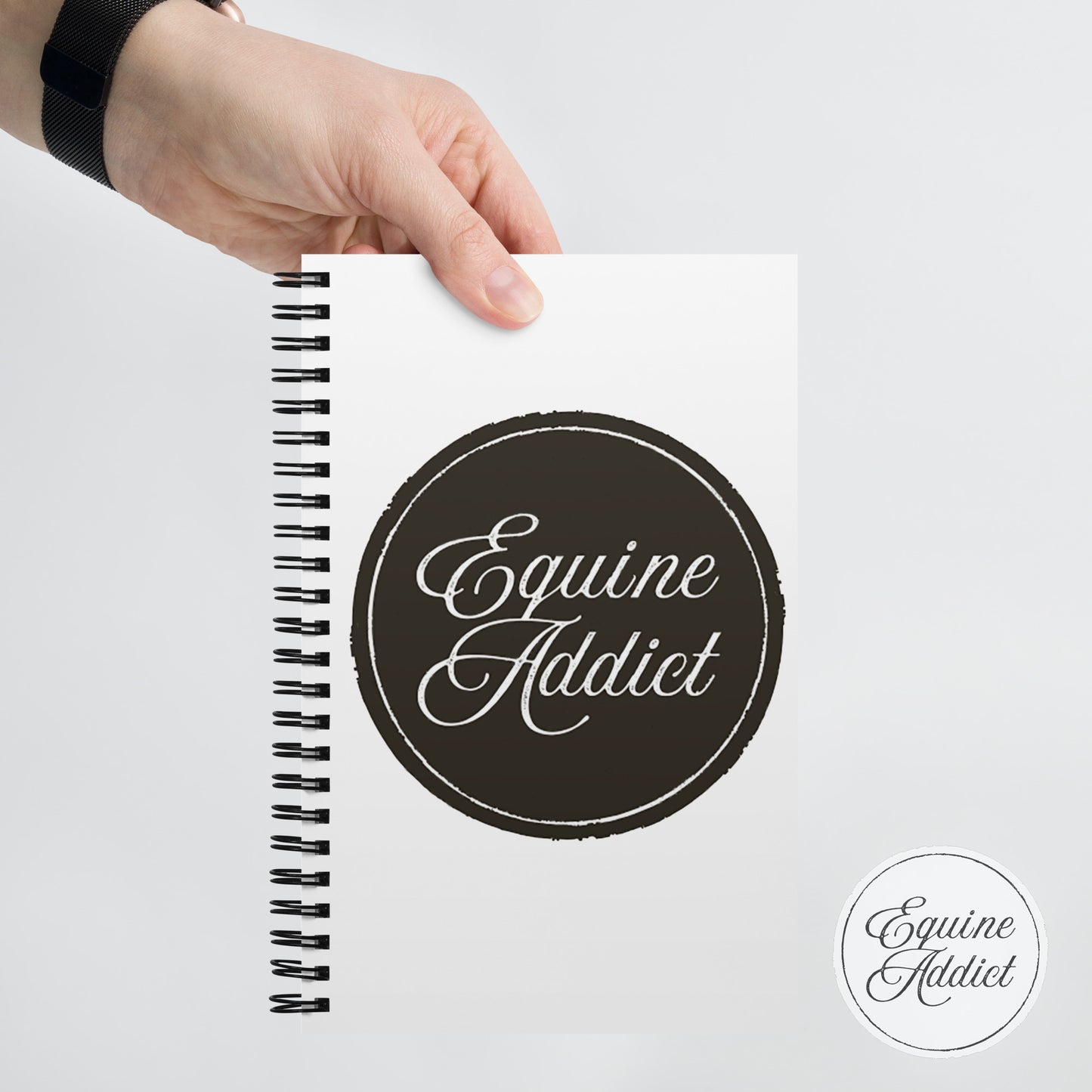 Notebook with 'Equine Addict' branding held by a hand on a light gray background. best notebook for horse girls, white spiral bound journal, horse lovers