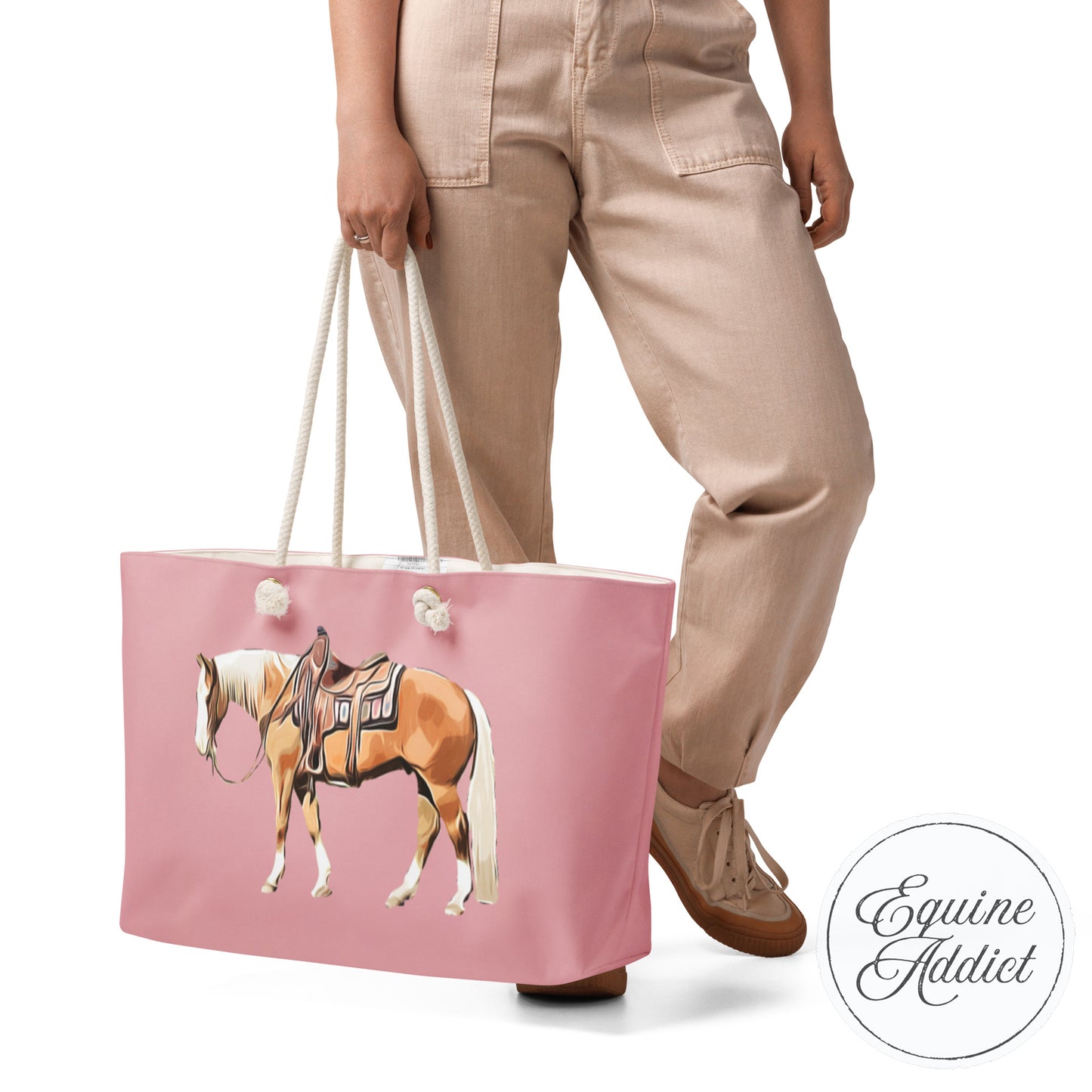 Person holding a pink tote bag with a horse design, wearing beige pants and brown shoes.