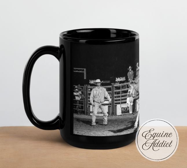 Black mug with a printed design of a person in a cowboy hat at a rodeo