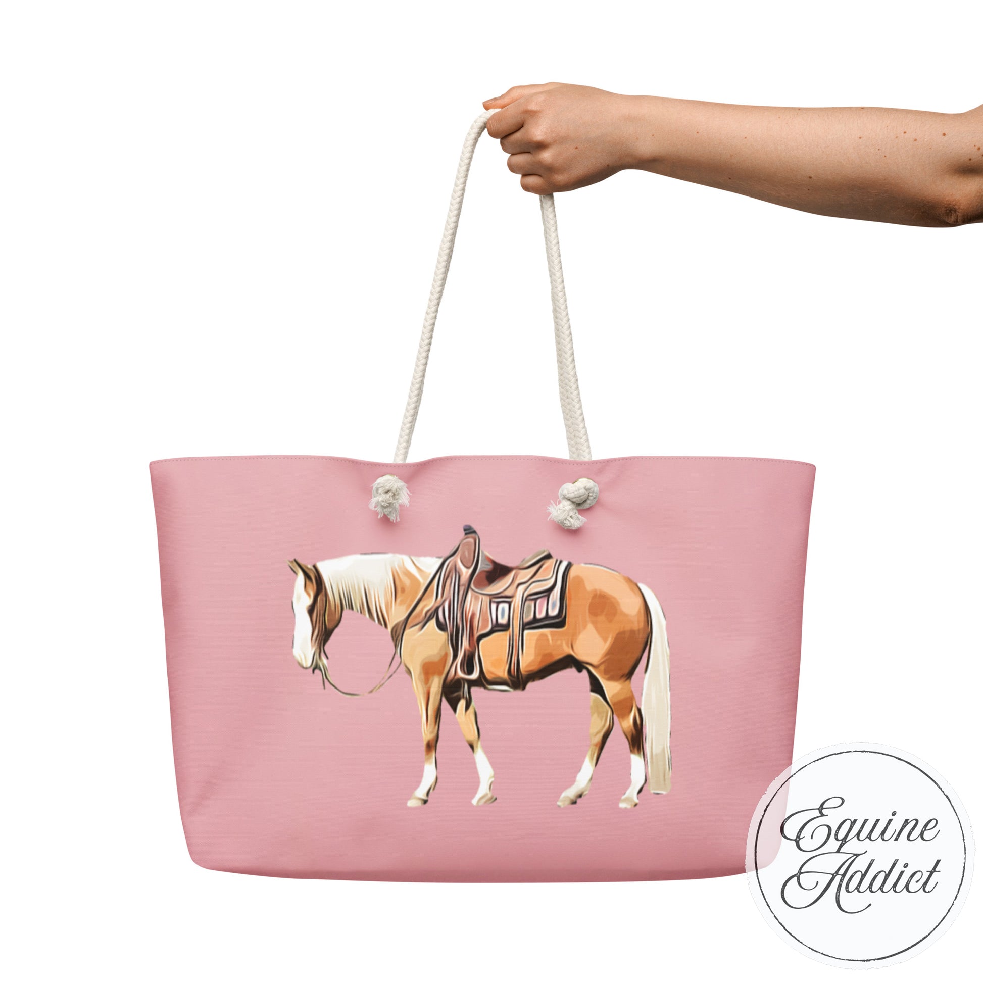 Pink tote bag with palomino horse design held by a hand on a white background.